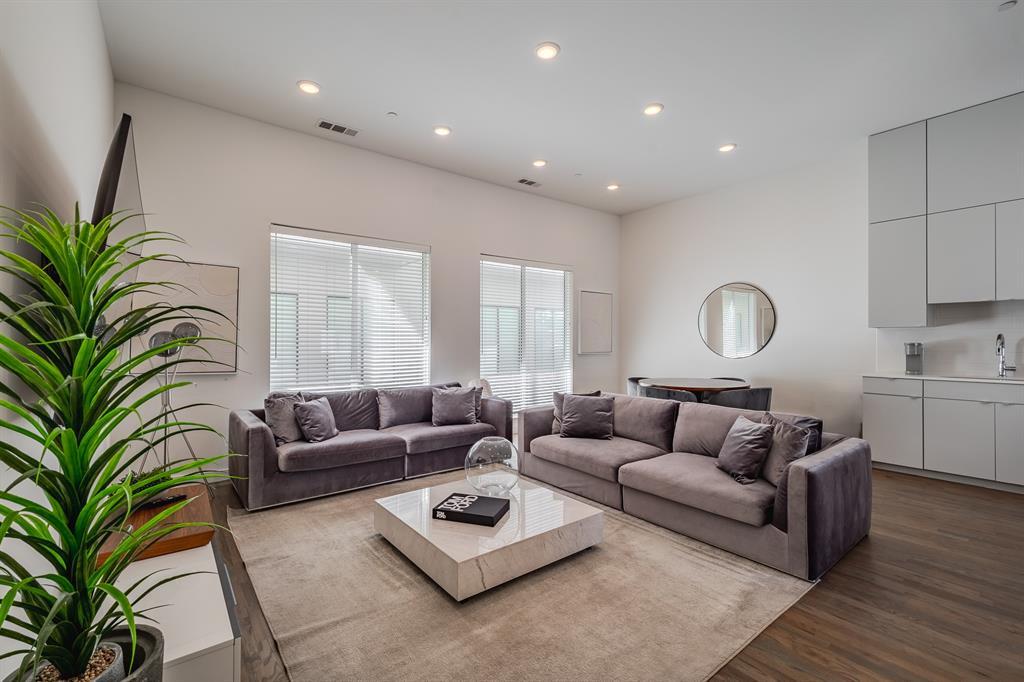 High ceilings, recessed lighting, wood-finish flooring, and built-in minimalist cabinetry with an integrated sink