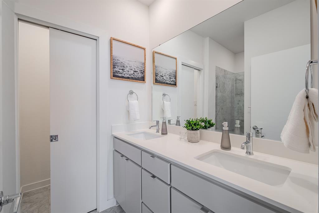 Dual-sink vanity featuring a solid surface countertop, undermount rectangular basins, chrome-finish fixtures, and a large-format vanity mirror