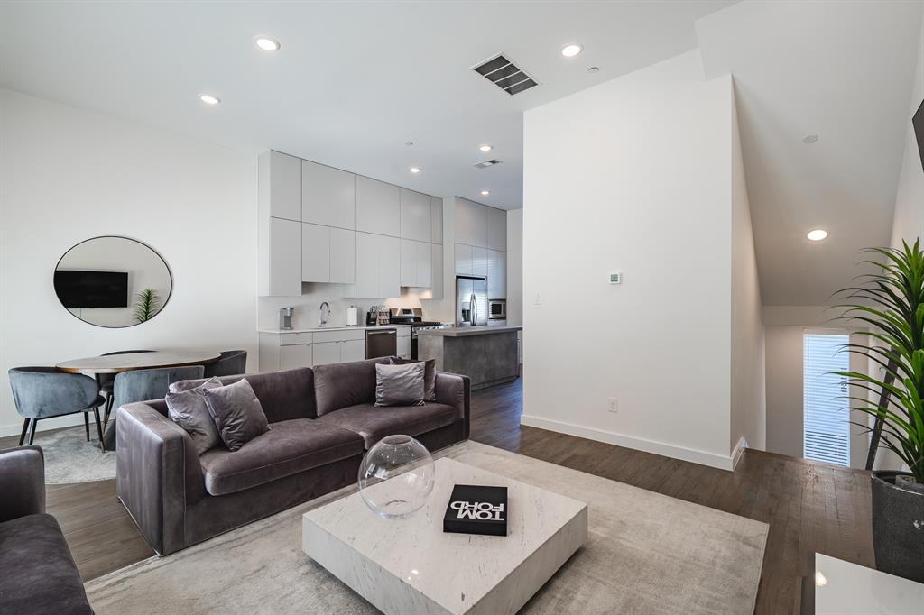 Kitchen featuring flat-panel cabinetry, a stone-finish kitchen island, recessed lighting, and wood-finish flooring
