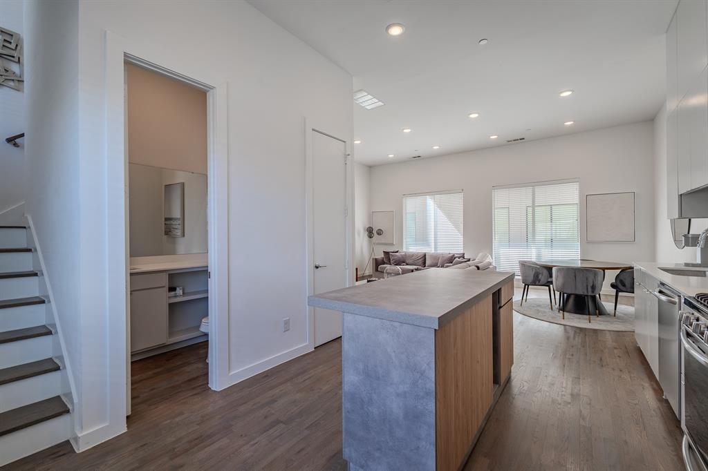 Kitchen island with concrete-finish countertop and wood-finish cabinetry, recessed ceiling lighting, wood-finish flooring, and high ceilings