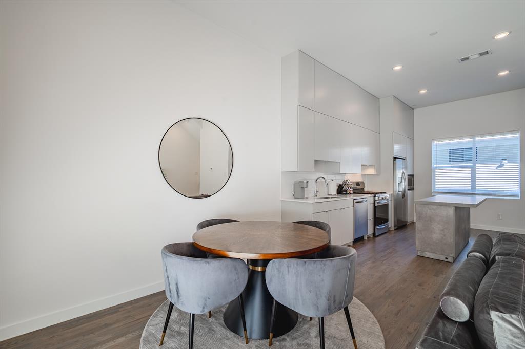 Kitchen featuring floor-to-ceiling cabinetry, stainless steel appliances, a stone-finish island, and wood-finish flooring with recessed lighting