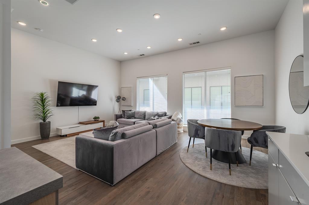 Open-concept interior featuring high ceilings, recessed lighting, wood-finish flooring, and large windows with horizontal blinds