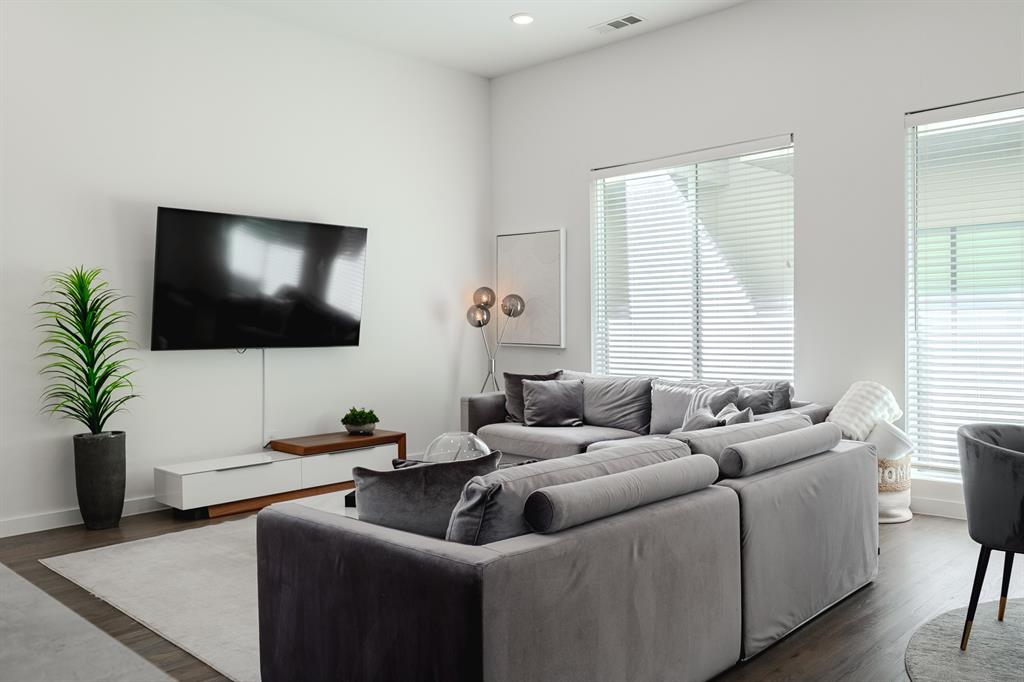 High-ceiling living area featuring recessed lighting, large windows with horizontal blinds, and dark wood-finish flooring