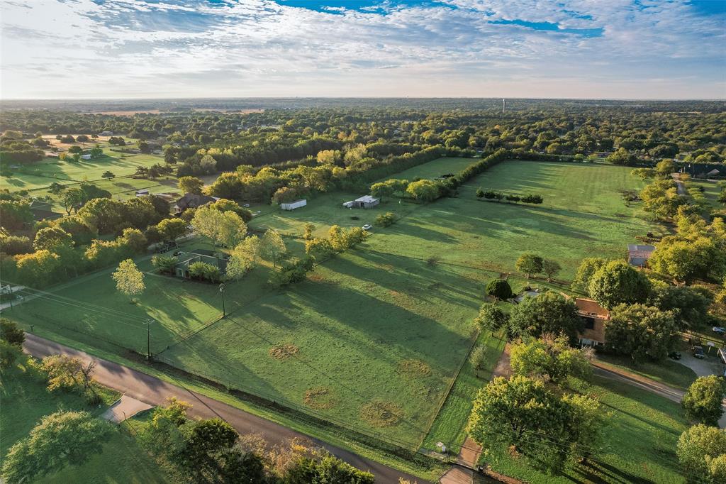 Aerial perspective of expansive acreage featuring mature hardwood trees, perimeter fencing, and open pasture land Aerial perspective of expansive acreage featuring mature hardwood trees, perimeter fencing, and open pasture land