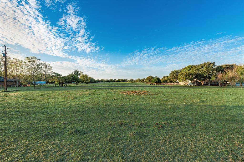 Expansive open acreage featuring level topography, mature perimeter trees, and wire perimeter fencing