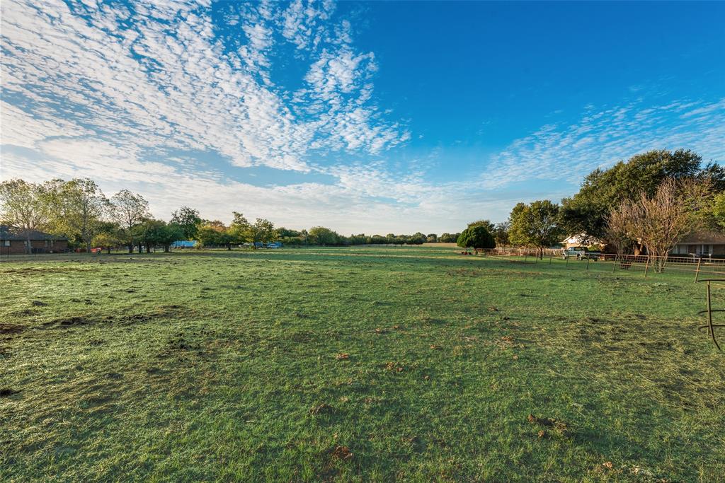 Expansive open pasture featuring mature trees and perimeter fencing