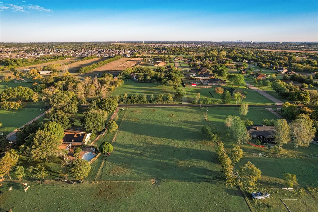 Aerial perspective of expansive acreage featuring vast open green space, mature tree lines, and a residential structure with an integrated swimming pool Aerial perspective of expansive acreage featuring vast open green space, mature tree lines, and a residential structure with an integrated swimming pool