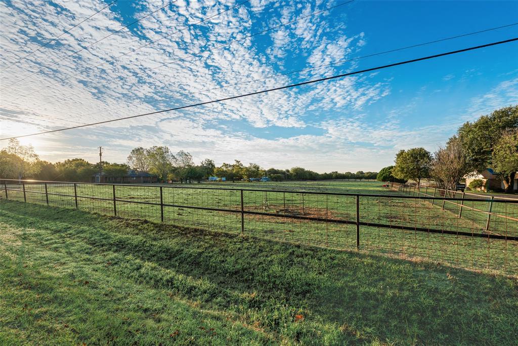 Expansive open acreage featuring manicured grass pasture, perimeter pipe fencing, and mature trees Expansive open acreage featuring manicured grass pasture, perimeter pipe fencing, and mature trees