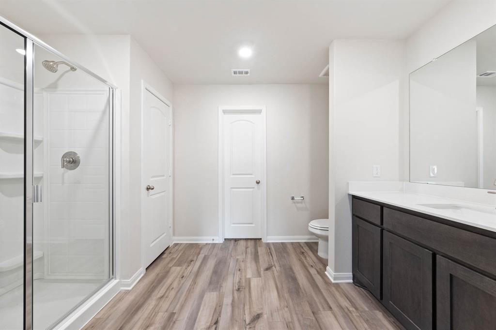 Bathroom with vanity, wood-type flooring, a shower with shower door, and toilet