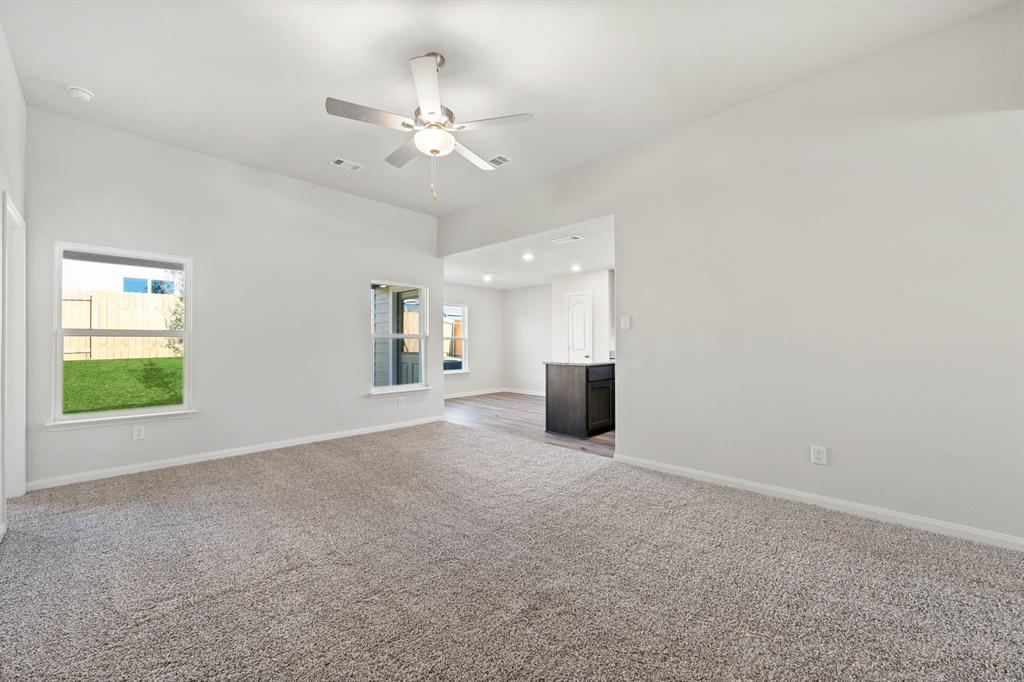 Unfurnished living room featuring ceiling fan, light colored carpet, and a healthy amount of sunlight Unfurnished living room featuring ceiling fan, light colored carpet, and a healthy amount of sunlight