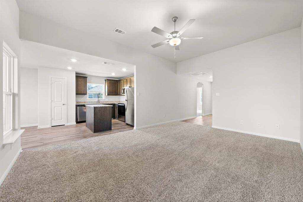 Unfurnished living room featuring carpet flooring, ceiling fan, and sink Unfurnished living room featuring carpet flooring, ceiling fan, and sink
