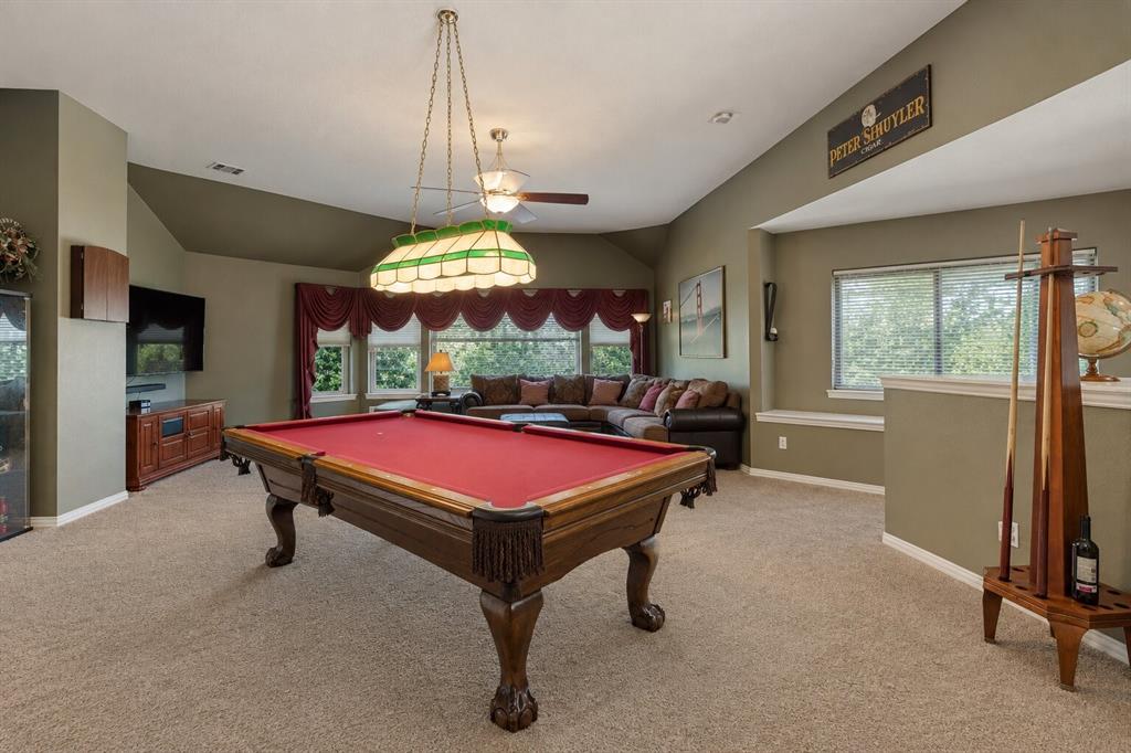 Vaulted ceilings with recessed lighting, multi-pane window configurations, and a decorative stained-glass billiard light fixture