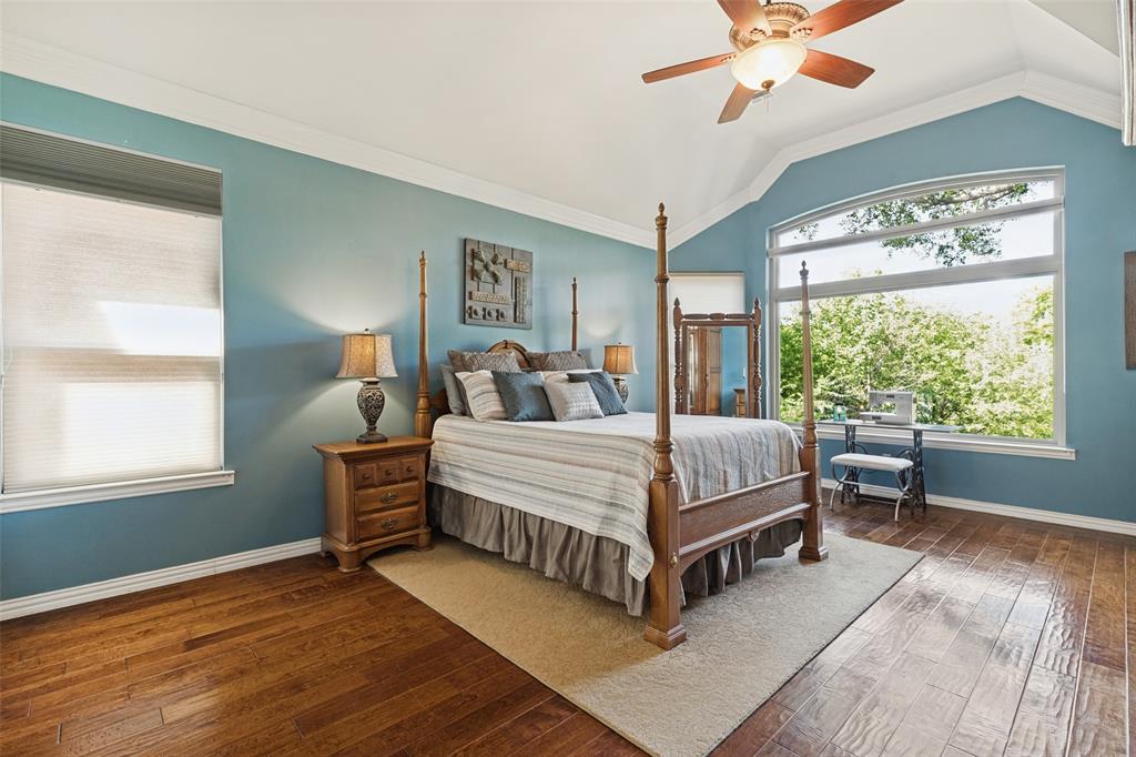Vaulted ceilings, wood-finish flooring, expansive windows, and a ceiling fan with integrated light fixture