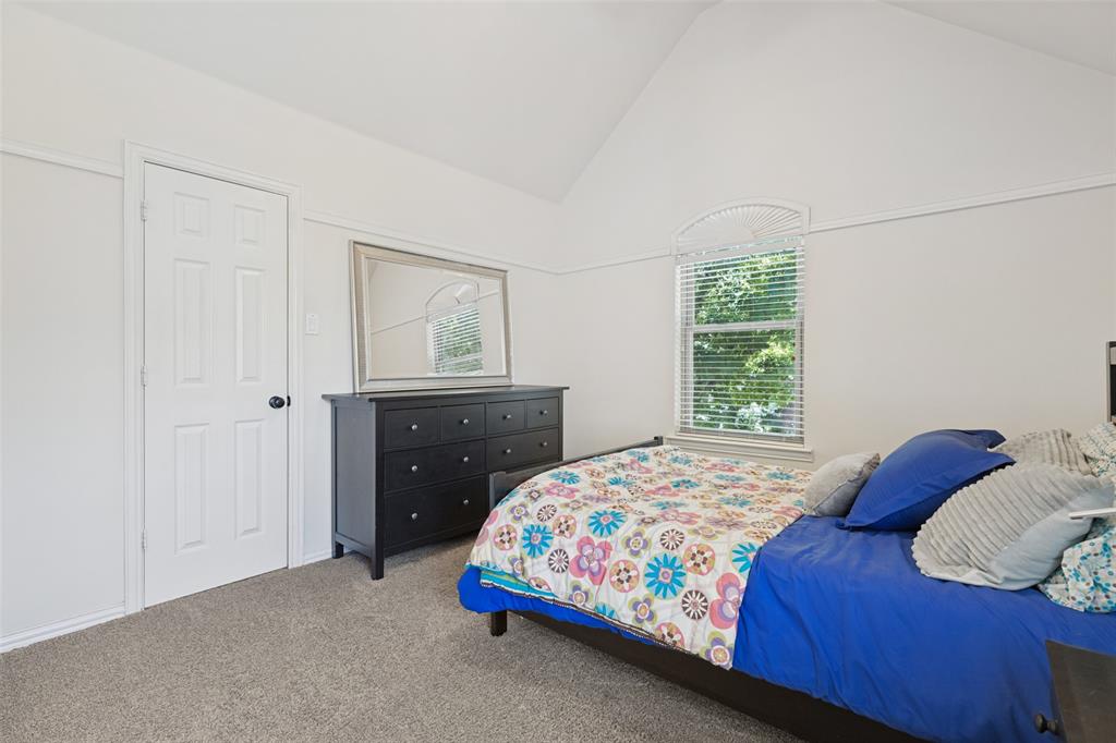 Vaulted ceiling, neutral wall tones, carpeted flooring, and a window with an arched transom
