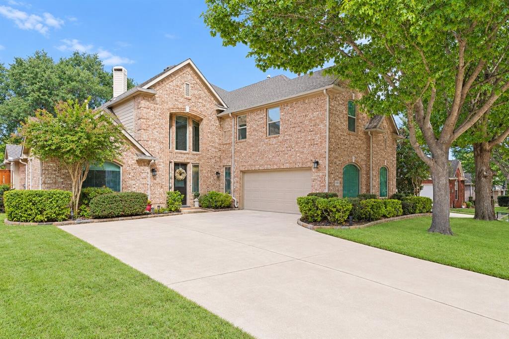 Multi-story brick exterior featuring a multi-gabled roofline, an arched entryway, and an attached two-car garage