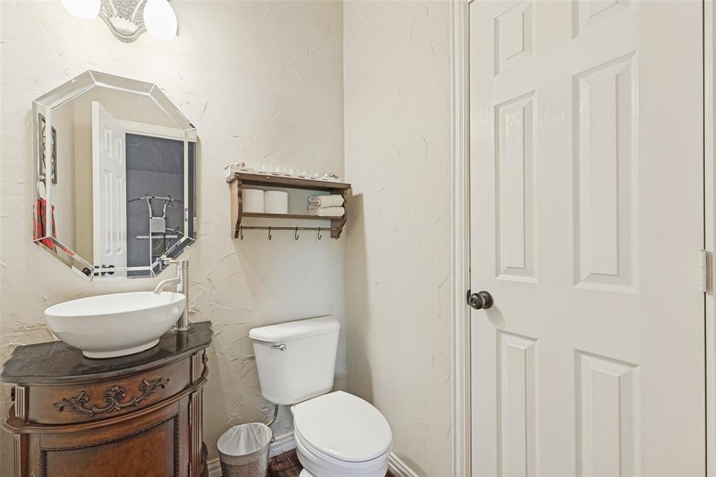 Octagonal wall mirror, vessel sink with high-arc faucet, stone-top vanity, textured wall finish, and six-panel interior door