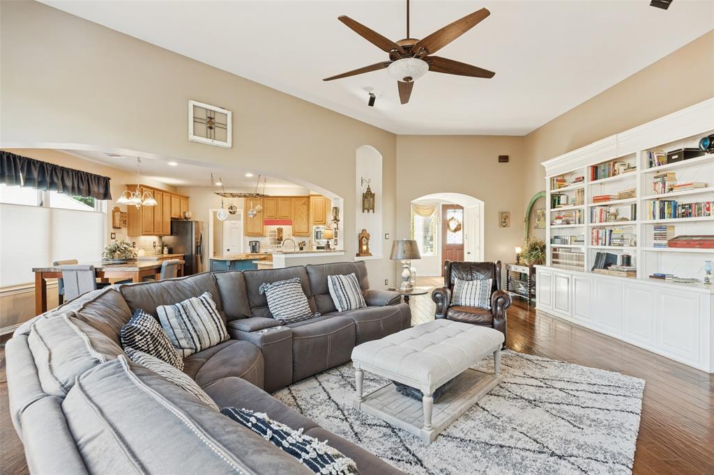 Vaulted ceilings, built-in floor-to-ceiling cabinetry, arched architectural detailing, and wood-finish flooring