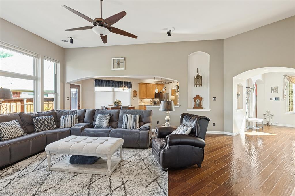 Vaulted ceilings with a multi-blade ceiling fan, expansive wood-finish flooring, arched architectural detailing, and recessed wall niches