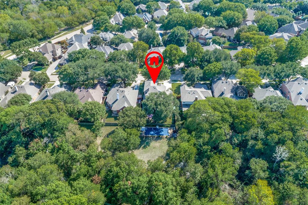 Aerial perspective featuring a residential lot with a rectangular swimming pool, expansive wooded grounds, and mature tree canopy