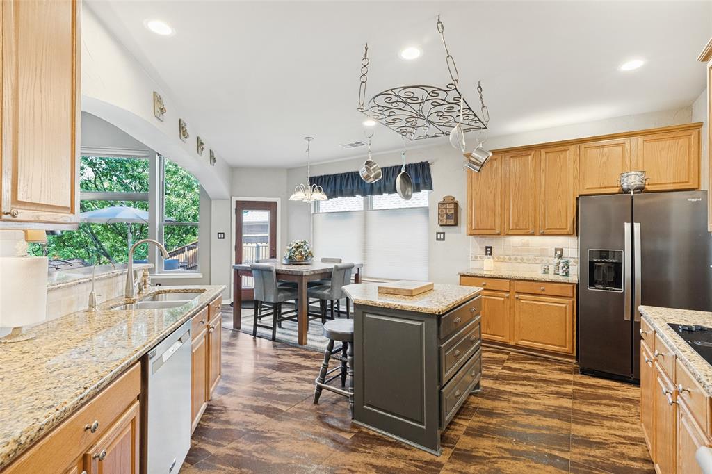 Kitchen featuring wood cabinetry, stone countertops, wood-finish flooring, a central island with storage, and a ceiling-mounted metal pot rack