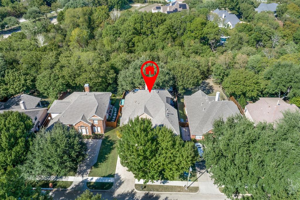 Aerial perspective of residential property featuring a multi-gabled roofline and dense perimeter of mature trees