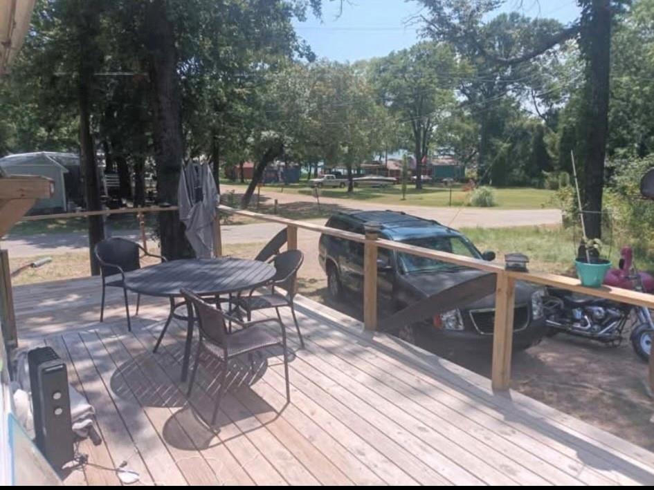 Elevated wood-plank deck featuring a wooden railing with vertical balusters and mature surrounding trees