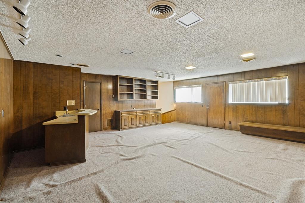 Upstairs game room with built-in bar, extensive wood paneling, built-ins and half bath