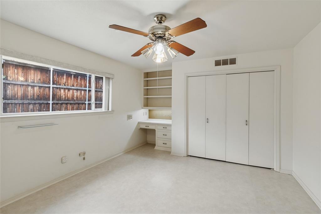 Split bedroom with a built-in desk with overhead shelving, ceiling fan and a double-door closet