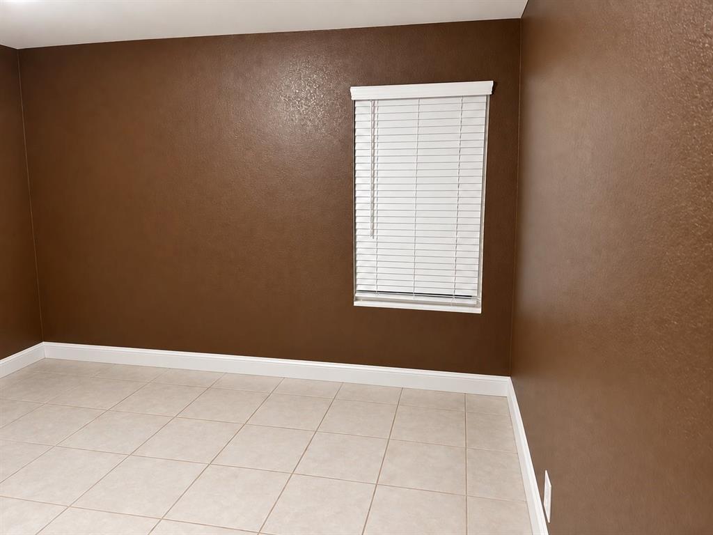 Room featuring smooth-texture walls, ceramic tile flooring, and a window with horizontal blinds