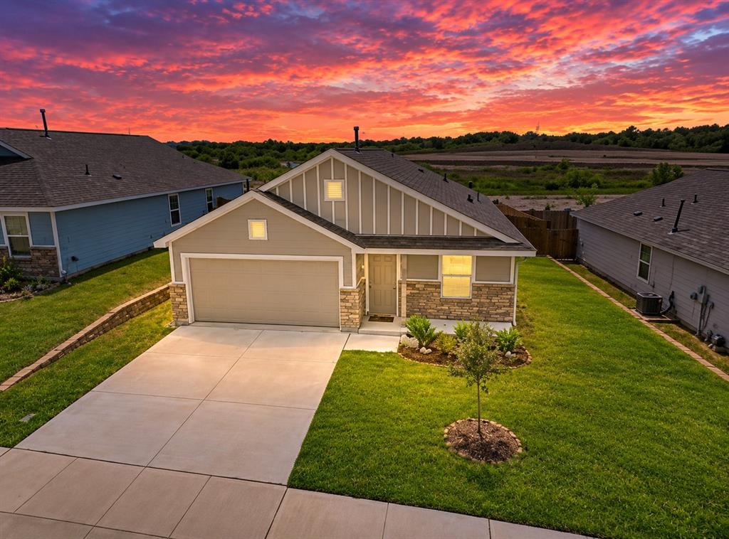 Single-story residence featuring vertical siding, stone masonry accents, an attached two-car garage, and a paved concrete driveway