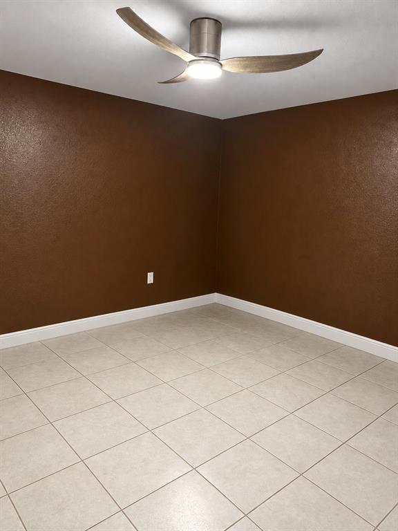 Ceramic tile flooring, textured wall finish, and a modern three-blade ceiling fan with an integrated light fixture