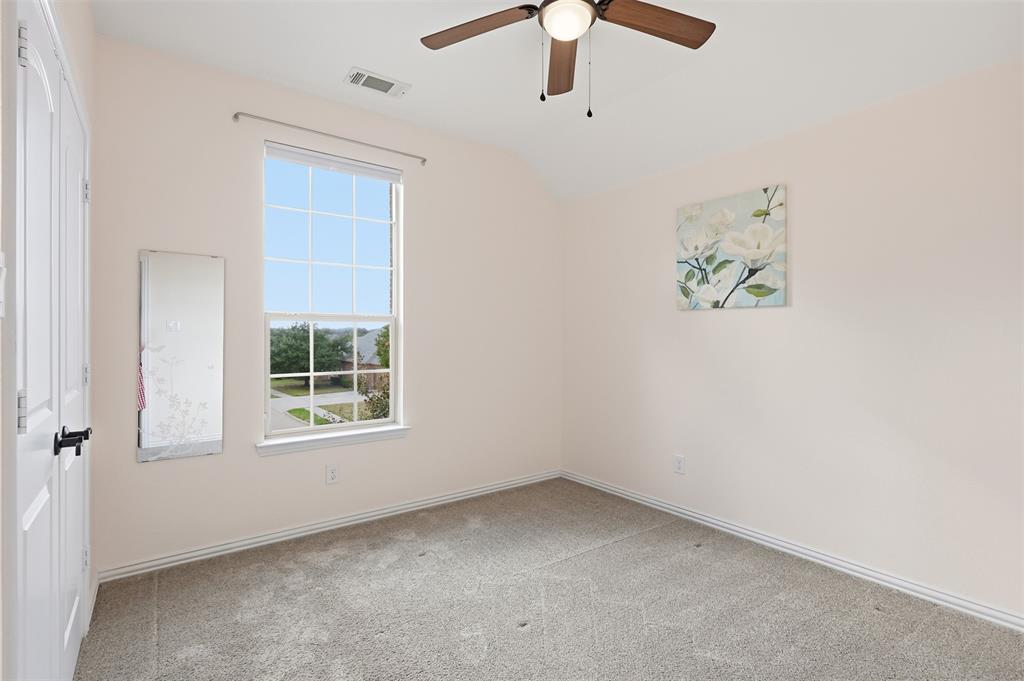 Room featuring neutral wall tones, carpeted flooring, a grid-patterned window, and a ceiling fan with integrated lighting