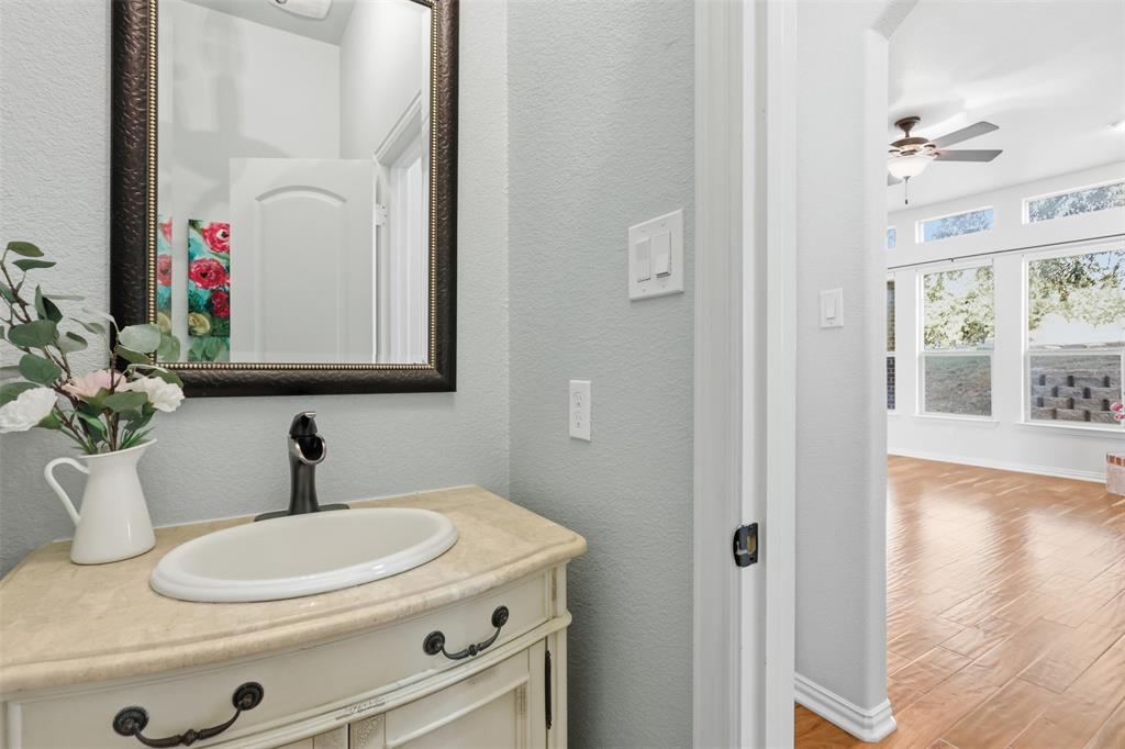 Vanity featuring a stone-look countertop, oval drop-in sink, and oil-rubbed bronze faucet, paired with a framed wall mirror