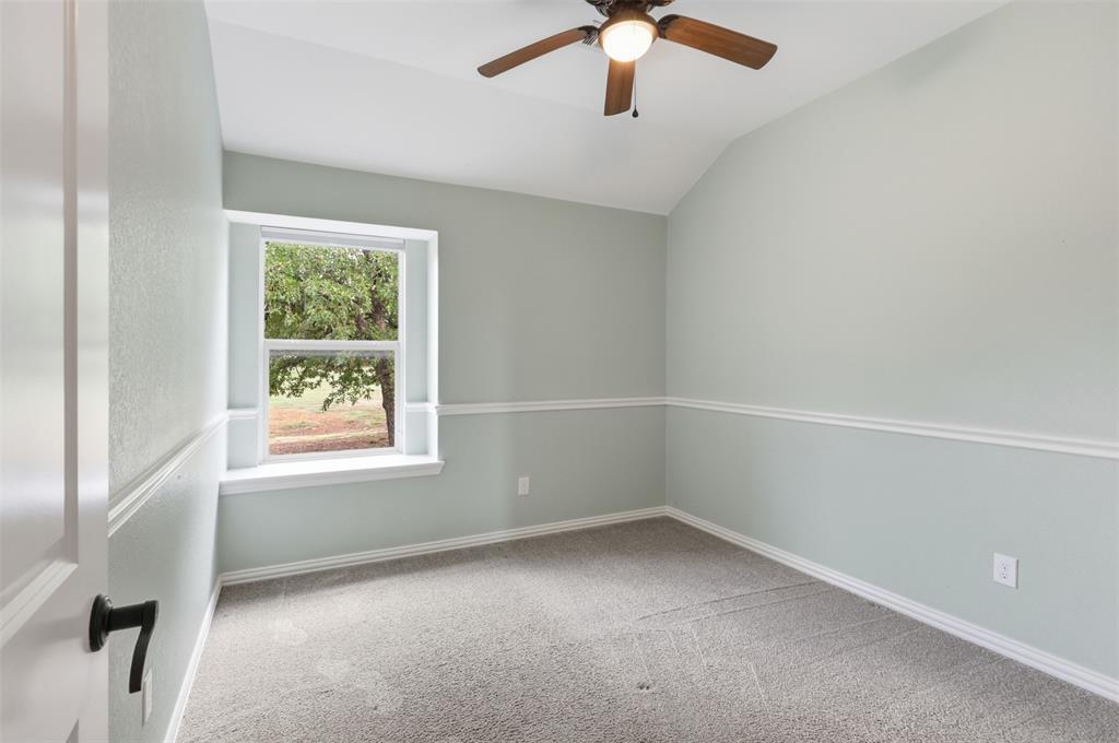 Interior room featuring a vaulted ceiling, neutral wall-to-wall carpeting, decorative chair rail molding, and a built-in ceiling fan with integrated lighting