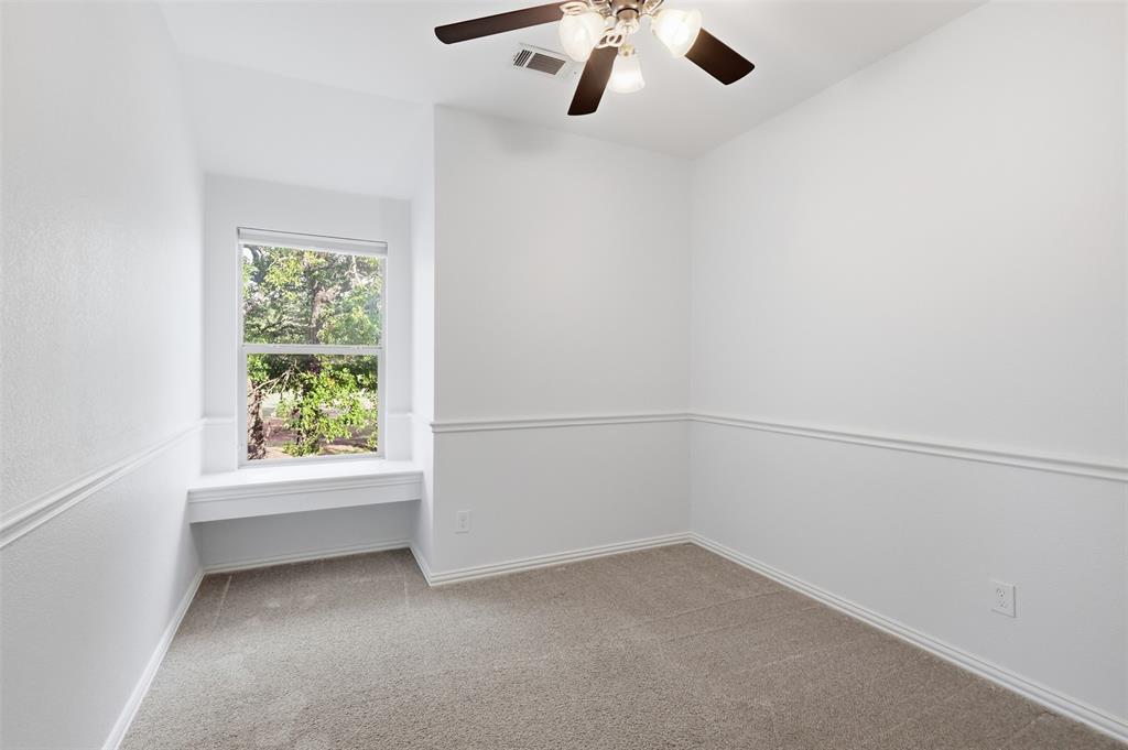 Interior room featuring neutral carpeting, a built-in window seat, chair rail molding, and a ceiling fan with integrated lighting