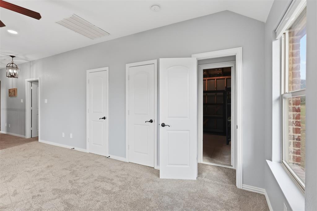Vaulted ceilings with recessed lighting, neutral carpeting, three-panel interior doors with matte black hardware, and an expansive window with a brick exterior surround