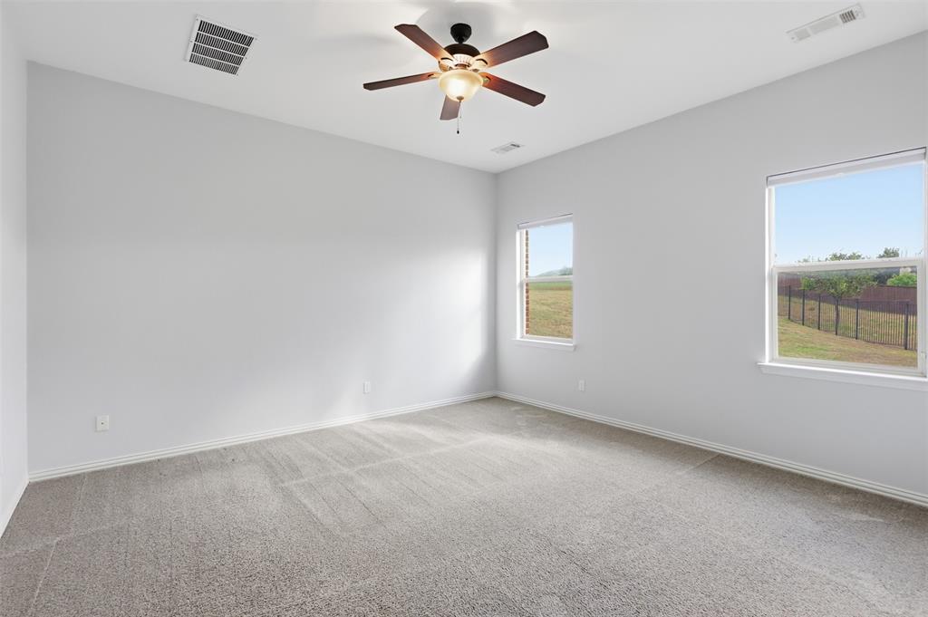 Neutral-toned room featuring neutral carpeting, a multi-blade ceiling fan with integrated lighting, and dual windows Neutral-toned room featuring neutral carpeting, a multi-blade ceiling fan with integrated lighting, and dual windows