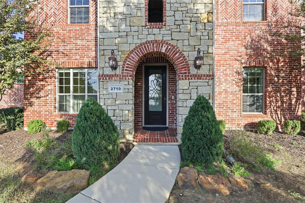 Brick exterior featuring a stacked-stone façade, arched entryway, and patterned masonry detailing
