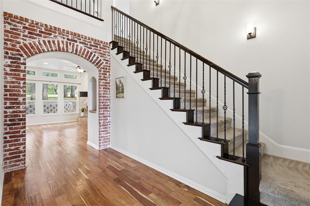 Staircase featuring a dark wood handrail, metal balusters, and carpeted treads Staircase featuring a dark wood handrail, metal balusters, and carpeted treads