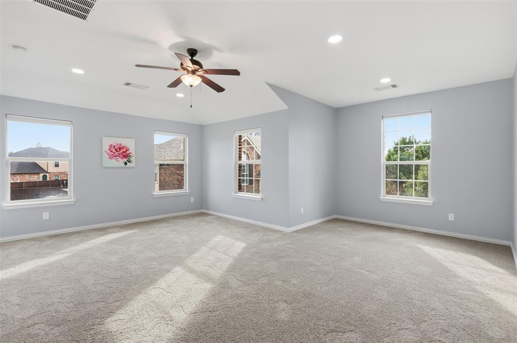 Spacious room featuring a vaulted ceiling, recessed lighting, neutral carpeting, and a multi-blade ceiling fan