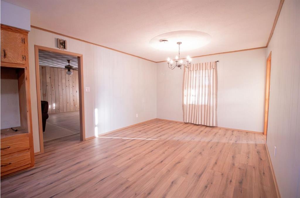 Interior room featuring wood-finish flooring, a built-in wood cabinetry unit, and a central multi-arm chandelier