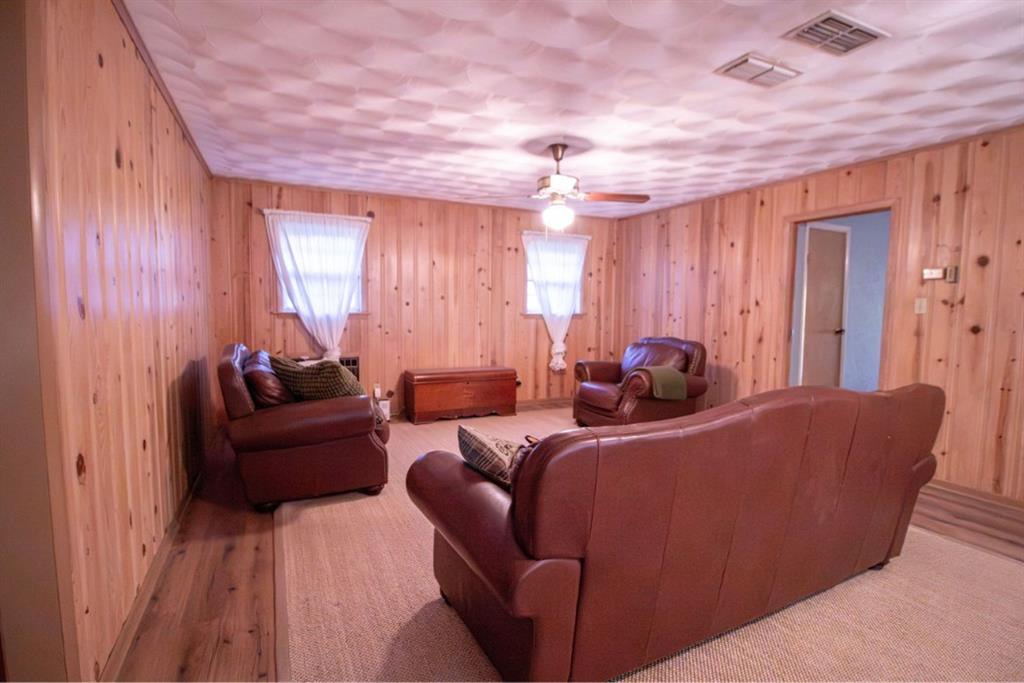 Interior space featuring full-height wood-paneled walls, a textured ceiling, and a central ceiling fan