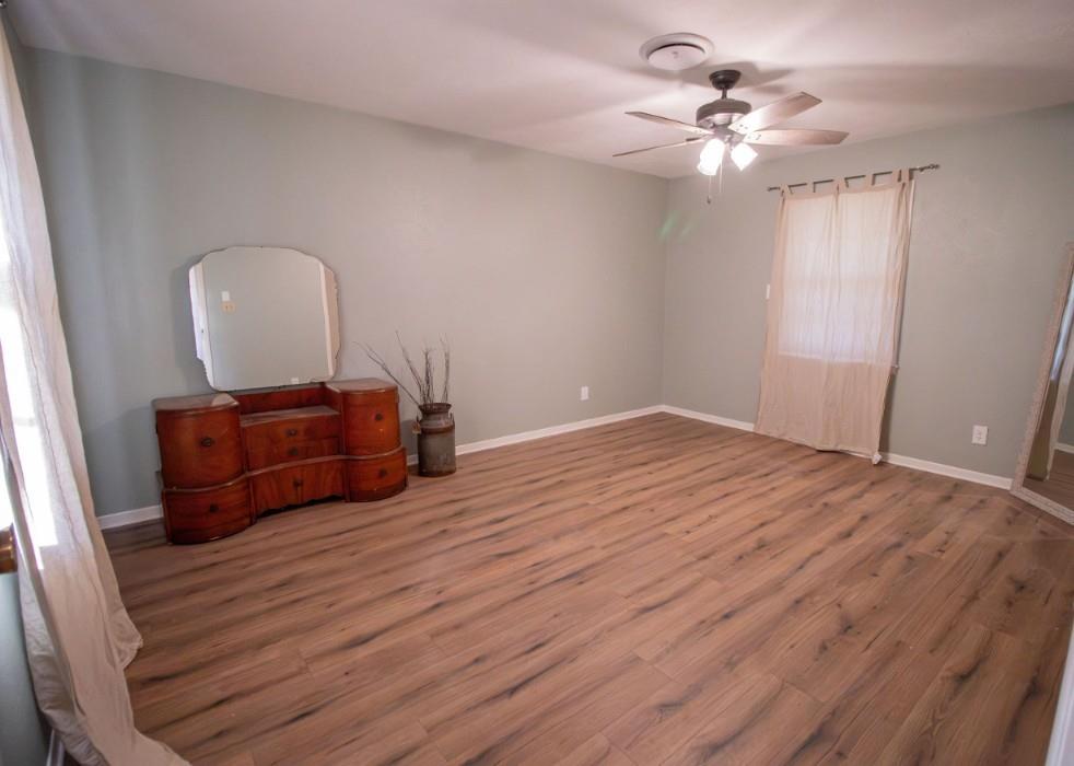 Room featuring wood-finish flooring, a ceiling fan with integrated lighting, and neutral wall tones
