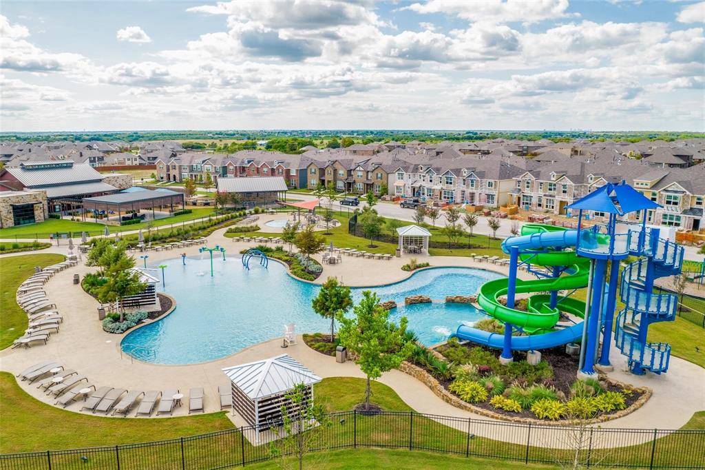 Community swimming facility featuring a multi-level water slide, aquatic play elements, a stone-accented pool, and multiple shade structures