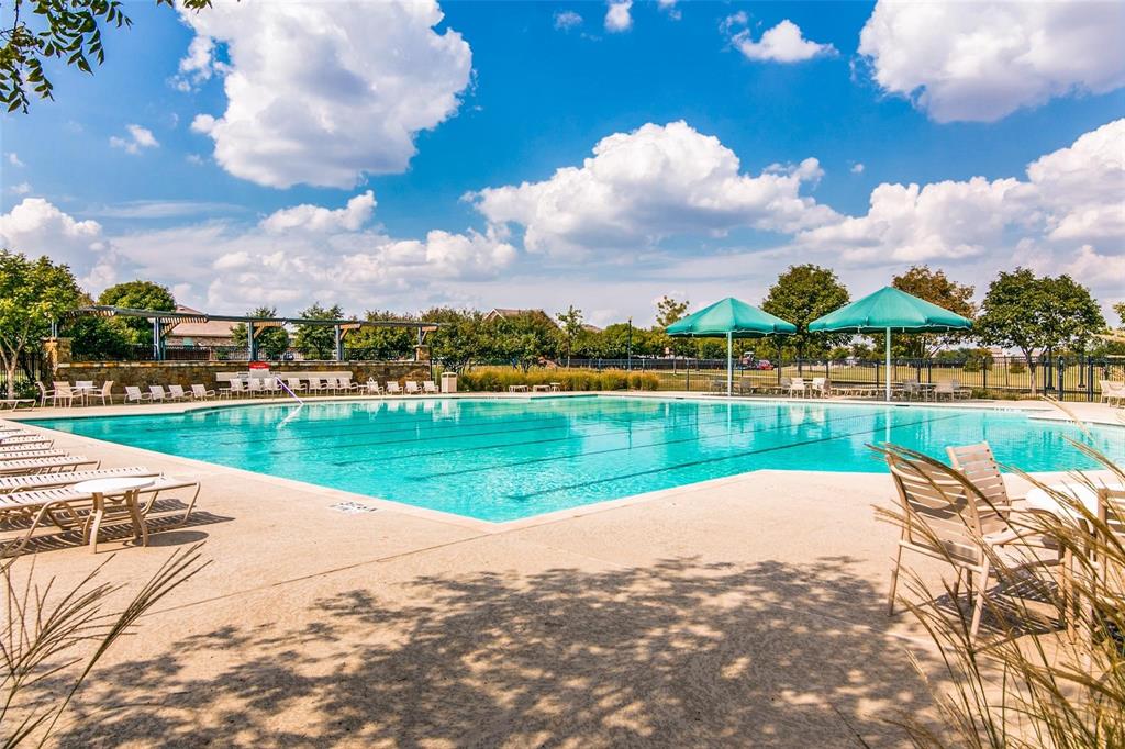 Large swimming pool featuring lap lanes, aggregate concrete decking, and integrated shade structures