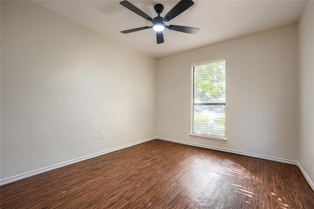 Wood-finish flooring, neutral walls, and a matte black ceiling fan with integrated lighting