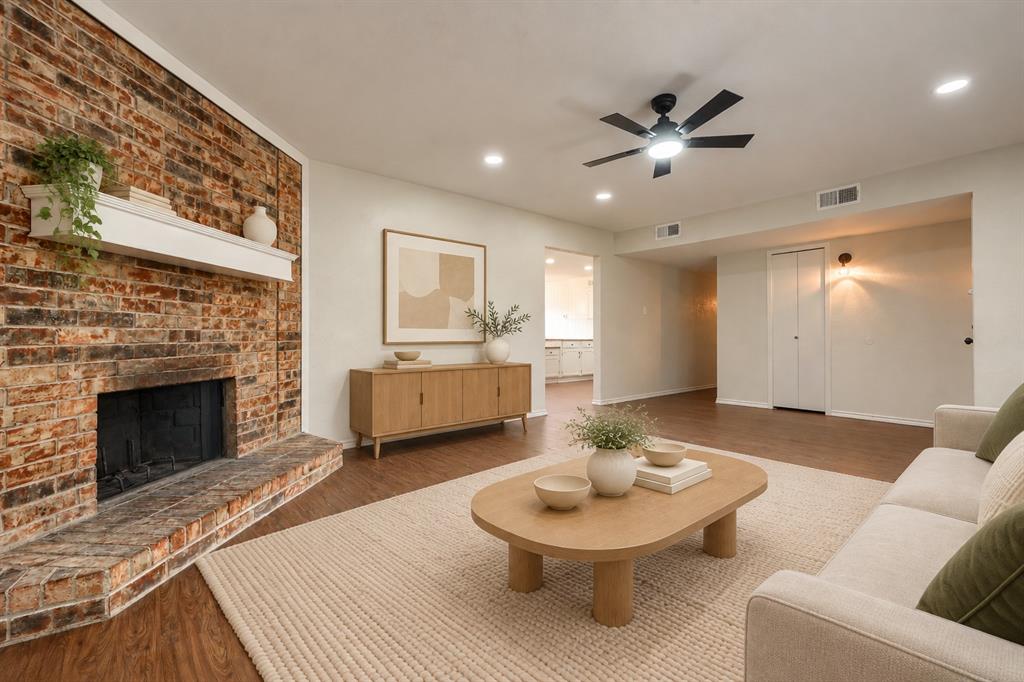 Floor-to-ceiling exposed brick fireplace with a white mantel, recessed lighting, wood-finish flooring, and a ceiling fan Floor-to-ceiling exposed brick fireplace with a white mantel, recessed lighting, wood-finish flooring, and a ceiling fan