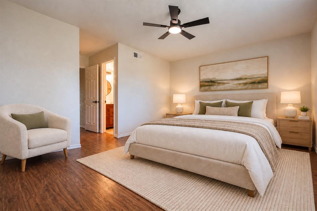 Bedroom featuring wood-finish flooring, a matte black ceiling fan with integrated lighting, and a six-panel interior door