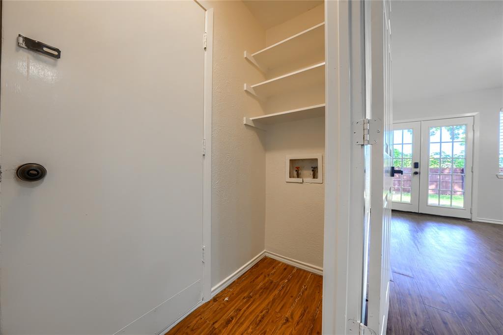 Dedicated laundry utility space featuring wood-finish flooring, built-in shelving, and plumbed hookups