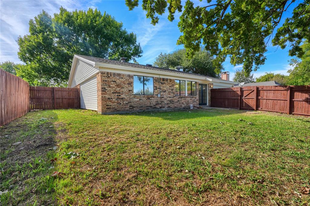 Exterior of the home featuring brick and siding construction, fenced backyard, and mature trees